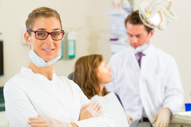 L'ambulatorio del dentista che guarda lo spettatore, nella sua collega sta curando una paziente