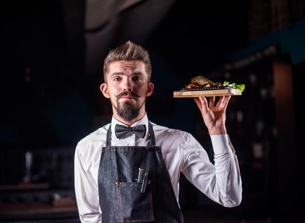 L'amichevole impiegato del ristorante serve un piatto appetitoso su uno sfondo nero