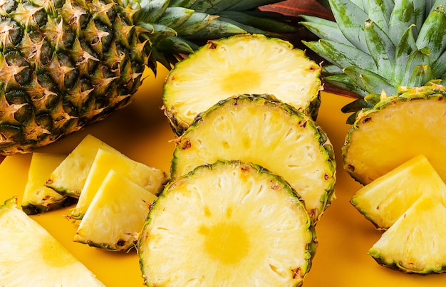 L'ananas tropicale maturo fresco ha tagliato in fette su uno scaffale giallo che si trova su una tavola di legno