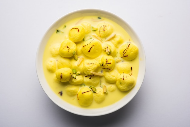 L'Angoori Rasmalai è un dessert indiano dolce con frutta secca e condimenti allo zafferano, servito in una ciotola su uno sfondo lunatico. messa a fuoco selettiva