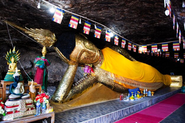 L'antica statua di Buddha reclinata nell'antica grotta di Wat Khao Phra Si Sanphet Chayaram tempio per i viaggiatori thailandesi visita visita rispetto preghiera benedizione il 7 novembre 2023 a Suphan Buri Thailandia
