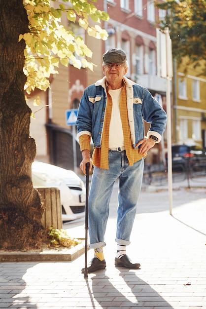 L'anziano elegante in abiti alla moda e con gli occhiali fa una passeggiata in città.