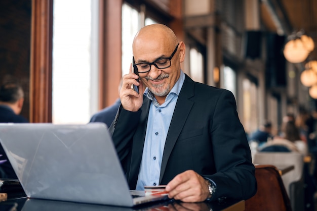 L'anziano si è vestito in vestito facendo uso dello Smart Phone e del carrello di credito per lo shopping online