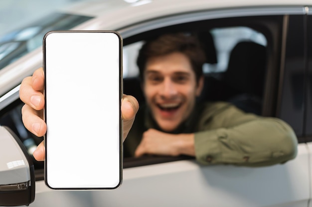 L'app di noleggio ha eccitato il giovane che dimostra uno smartphone vuoto mentre è seduto in macchina