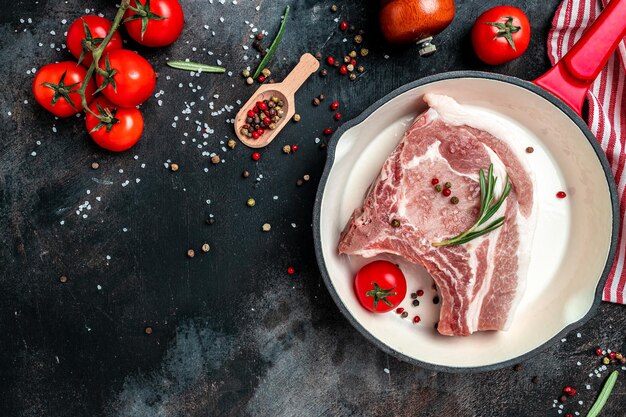 L'appetitosa bistecca di maiale cruda in padella è pronta per friggere la braciola su un osso per la vista dall'alto del testo