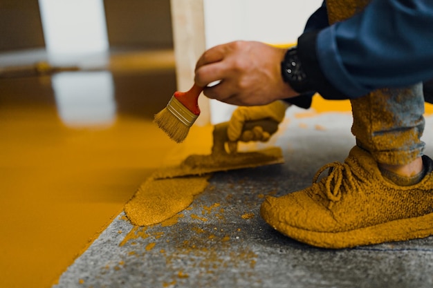 L'applicatore di pavimenti epossidici esegue lavori di verniciatura con malta epossidica poliuretanica