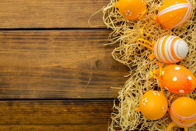 L&#39;arancia ha modellato le uova di Pasqua in un nido su una tavola di legno marrone. Vista dall&#39;alto, copia spazio.