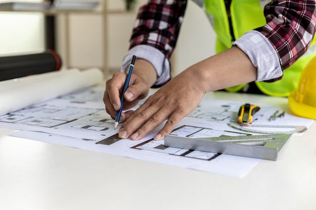 L'architetto maschio sta disegnando sui progetti della casa, sta controllando i piani della casa che ha progettato prima di inviarli ai clienti, sta progettando la casa e gli interni. Idee di design per la casa.