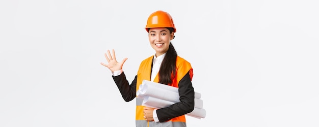 L'architetto professionista asiatico femminile ingegnere sorridente che dà cinque mesi per la costruzione porta il progetto del progetto e guardando la fotocamera garantisce il lavoro di finitura nel tempo su sfondo bianco