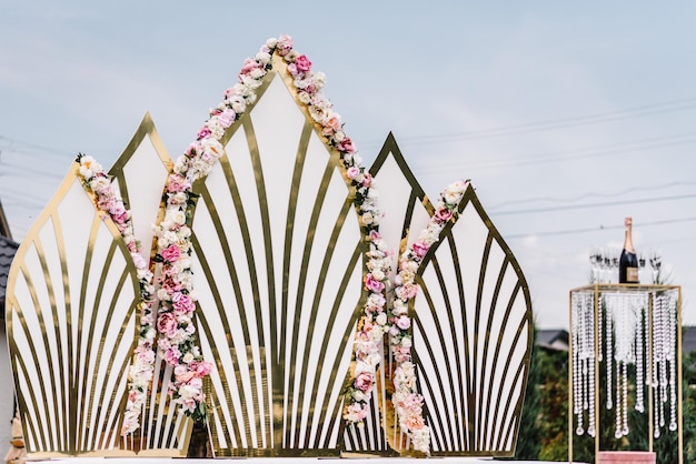 L'arco per la cerimonia di nozze è decorato con fiori nel cortile Decorazione in oro Decorazione floreale originale per matrimoni sulla parete Zona lounge del ricevimento di nozze