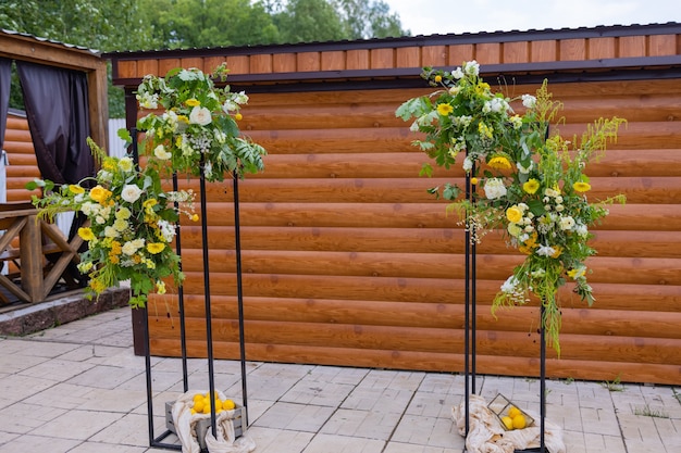 L'arco per la cerimonia nuziale, decorato con fiori di stoffa e verde, si trova in una pineta.