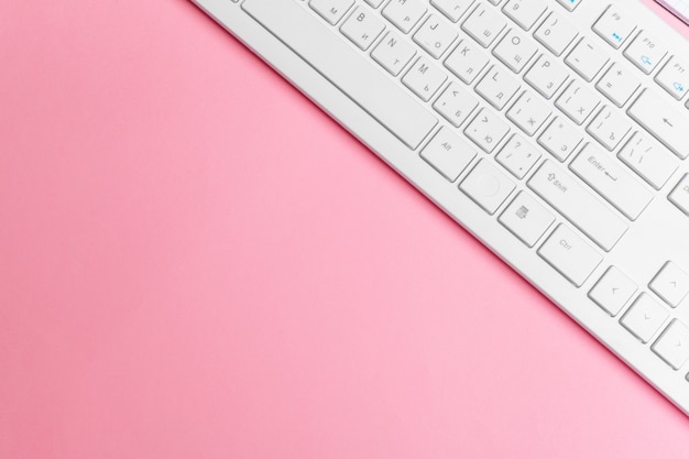 L'area di lavoro creativa rosa della donna con la tastiera e i rifornimenti di computer, vista superiore