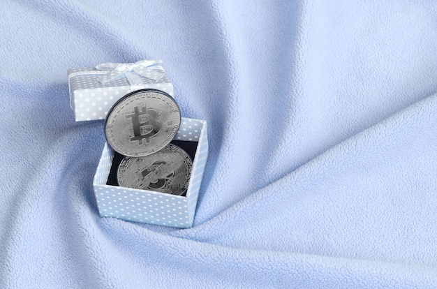 L&#39;argento bitcoin si trova in una piccola scatola regalo blu con un piccolo fiocco