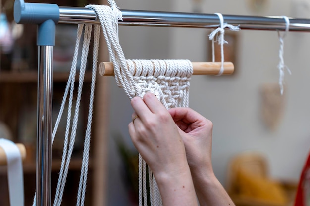 L'arte di fare i nodi Le mani di una giovane donna che fa il macrame