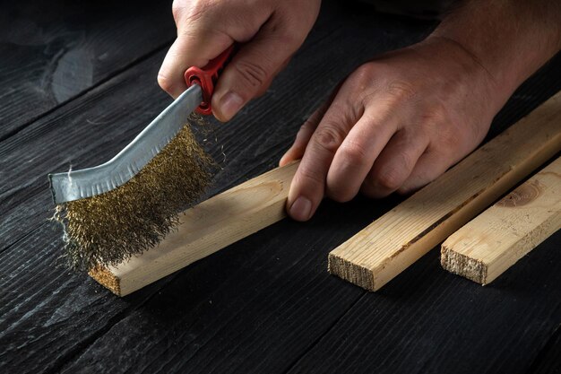 L'artigiano professionista pulisce la tavola di legno con uno strumento abrasivo Primo piano delle mani del costruttore Idea di ristrutturazione o costruzione