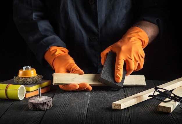 L'artigiano pulisce le assi di legno con strumenti abrasivi