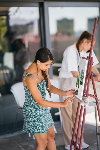 L'artista della giovane donna dipinge con una spatola sulla tela