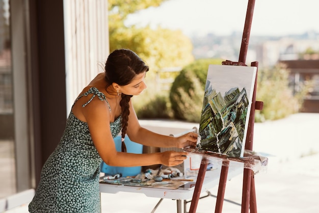 L'artista della giovane donna dipinge con una spatola sulla tela