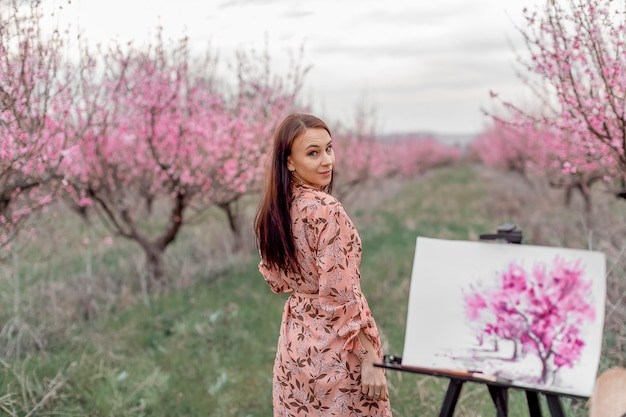 L'artista della ragazza dipinge un frutteto di pesche in una primavera di frutteto di pesche