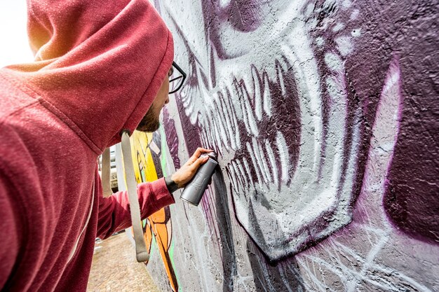 L'artista di strada dipinge graffiti colorati sul muro pubblico