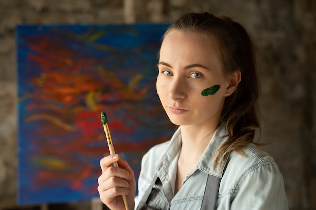 L'artista femminile applica la vernice verde sul viso con un pennello