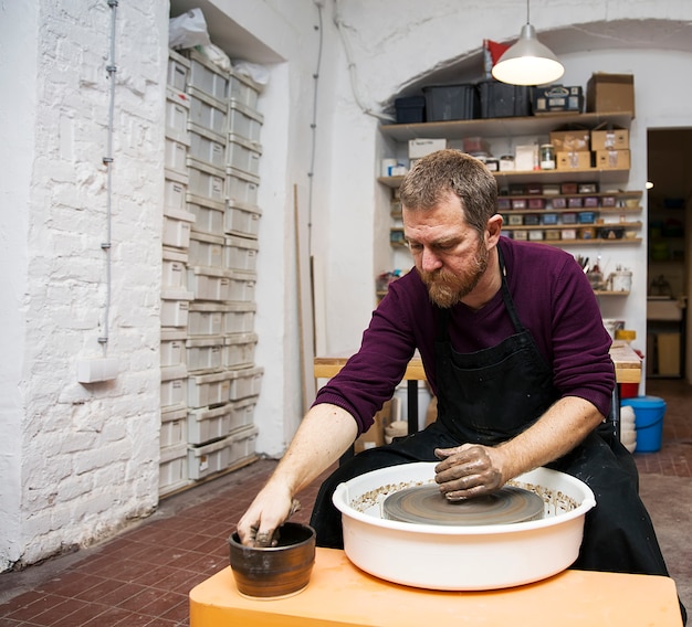 L&#39;artista maschio produce ceramica di argilla su una ruota di rotazione