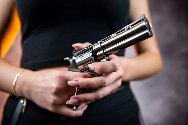 L'assassino femminile sottile indossa una giacca nera con una pistola nera isolata