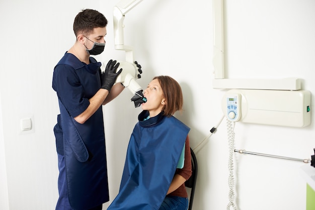 L'assistente dentista fa una radiografia dei denti a una giovane donna in un moderno centro medico