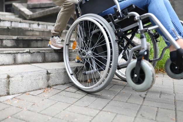 L'assistente sociale aiuta le persone disabili in sedia a rotelle a salire le scale