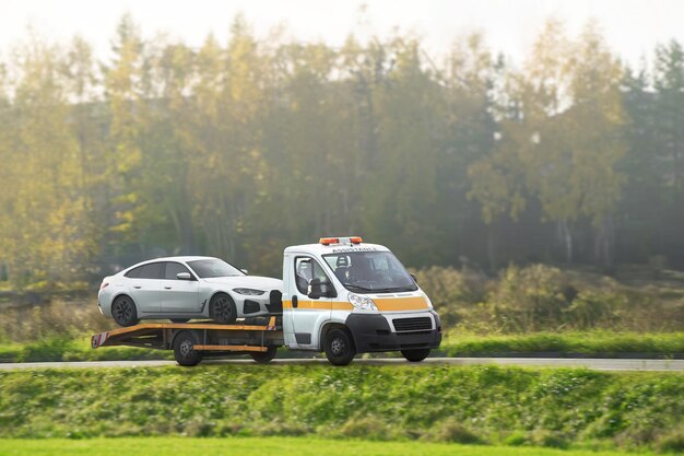 L'assistenza stradale trasporta un'auto con un guasto sulla strada Rollback camion di rimorchio Un camion di remorchio consegna un veicolo guastato L'aiuto stradale aiuta un conducente in difficoltà