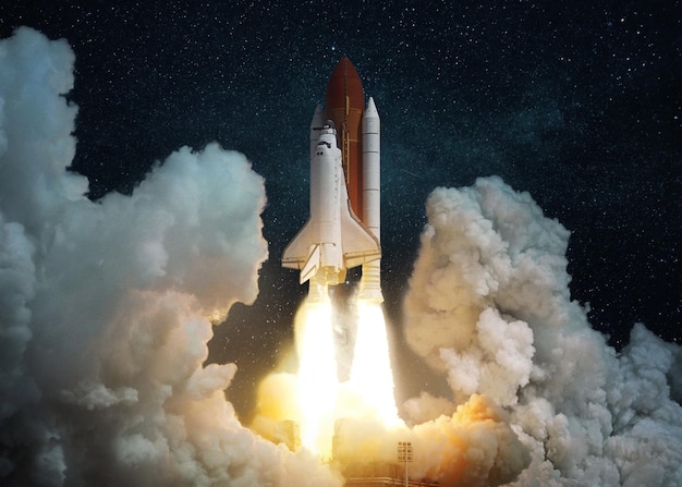 L'astronave con esplosione e nuvole di fumo si alza nel cielo azzurro stellato Lancio riuscito della navetta spaziale il completamento di una missione spaziale Decollo del razzo