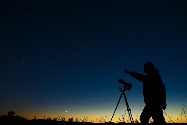 L'astronomo fotografa il cielo stellato notturno su una fotocamera digitale utilizzando un treppiede.