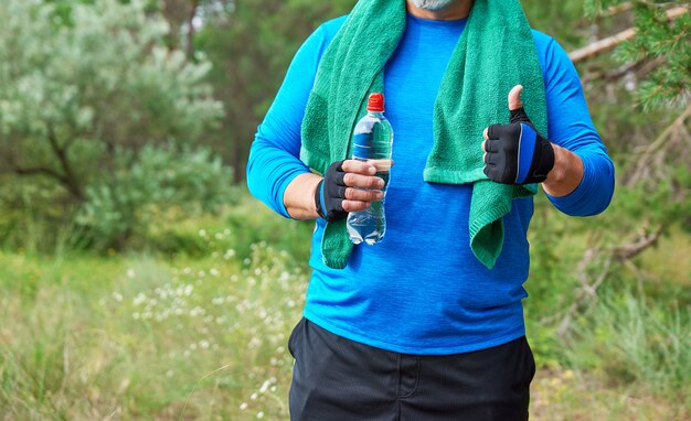 L&#39;atleta adulto sta stando in mezzo alla natura in un&#39;uniforme blu con un asciugamano verde