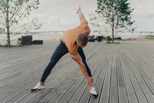 L'atleta motivato riscalda gli esercizi sul lungomare Corridore sano di stile di vita attivo