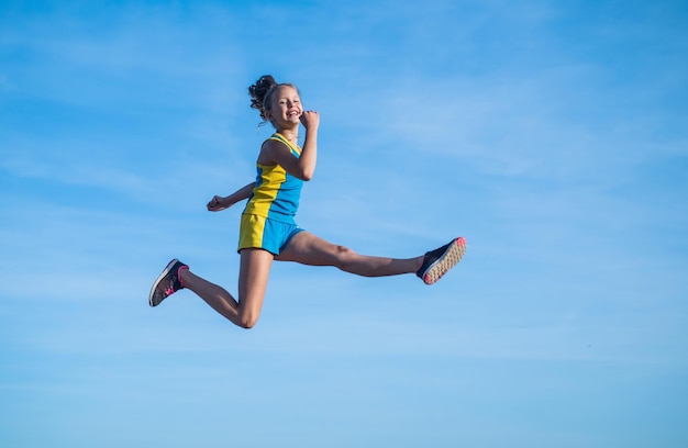 L'atleta o il ginnasta allegro del bambino salta sull'energia del fondo del cielo