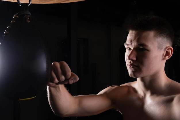 L'atleta pratica il sacco soffia guanto boxer nero giovane professionista pugilato per muscoli forti