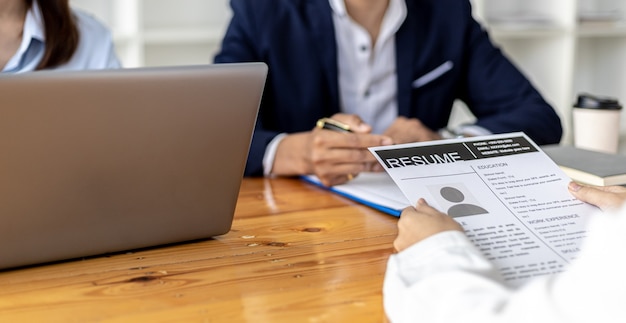 L'atmosfera della stanza dei colloqui nella start-up, il richiedente sta consegnando il curriculum all'intervistatore come documento di supporto per l'intervista, due intervistatori. Concetto di colloquio di lavoro