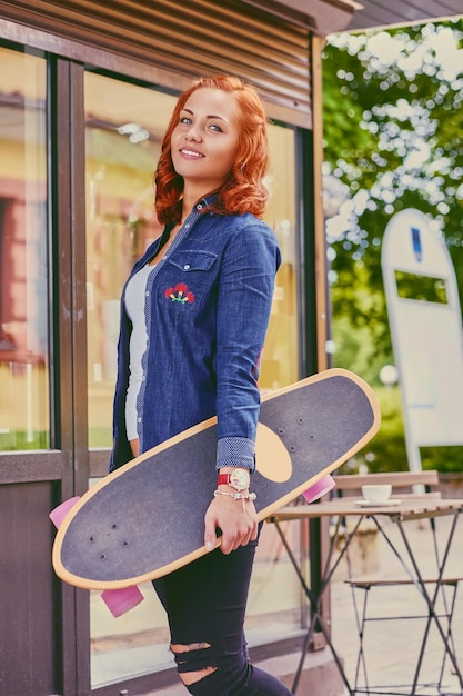 L'attraente donna rossa tiene in mano un Longboard.