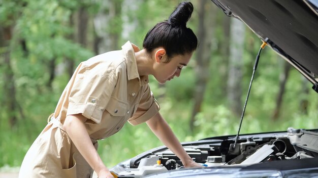 L'autista donna dai capelli neri cerca di risolvere da sola il problema in un'auto moderna. Una donna d'affari cerca i difetti e cerca di riparare il primo piano dell'automobile