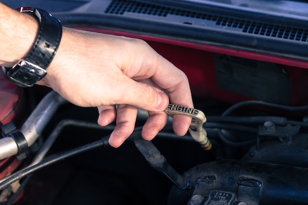 L'autista estrae un'asta di livello dell'automobile per controllare il livello dell'olio dell'auto.