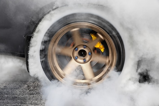 L'auto da corsa di trascinamento brucia la gomma dalle gomme in preparazione della gara