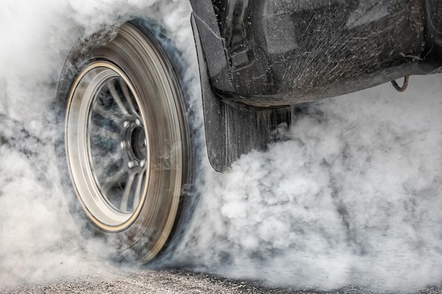 L'auto da corsa di trascinamento brucia la gomma dalle gomme in preparazione della gara