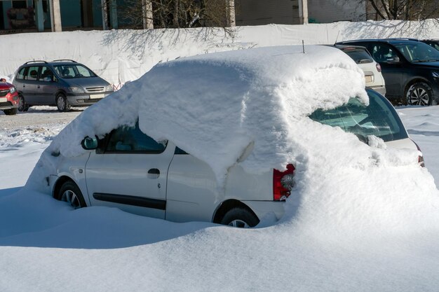 L'auto nel parcheggio è completamente innevata Problemi dopo abbondanti nevicate Grandi cumuli di neve nel parcheggio e sulle strade