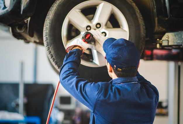 L'automobile cambiante del meccanico spinge dentro l'officina riparazioni automatica