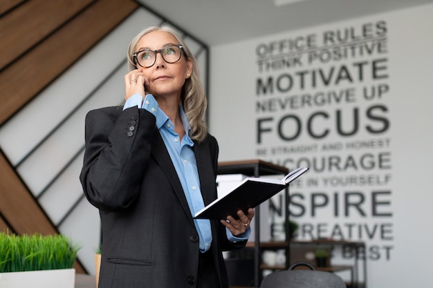 L'economista femminile adulto maturo con i capelli grigi parla al telefono in ufficio