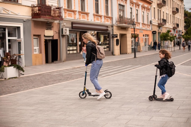 L'elegante giovane mamma e figlia stanno guidando uno scooter