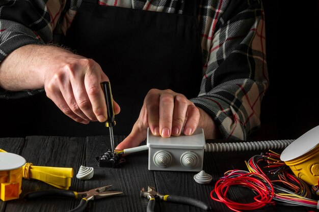 l'elettricista avvita il filo al connettore con le mani del cacciavite del maestro in officina