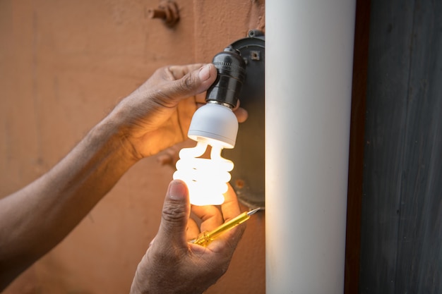 L&#39;elettricista cambia la lampadina in lampada da parete esterna della casa