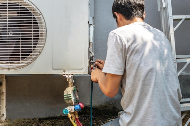 L'elettricista che ripara il condizionatore d'aria Il tecnico sta controllando il compressore d'aria fresco