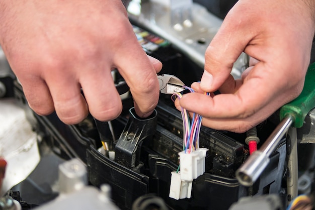 L&#39;elettricista dell&#39;automobile ripara l&#39;automobile, il tester e le micce e le pinze